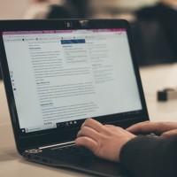 person typing on a computer with wordpress logo on his shirt