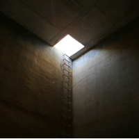 a small hole in the ceiling with a ladder to climb out of