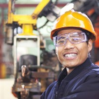man smiling with a hard hat and safety glasses on
