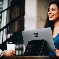 a woman smiling as she rings a customer out for coffee