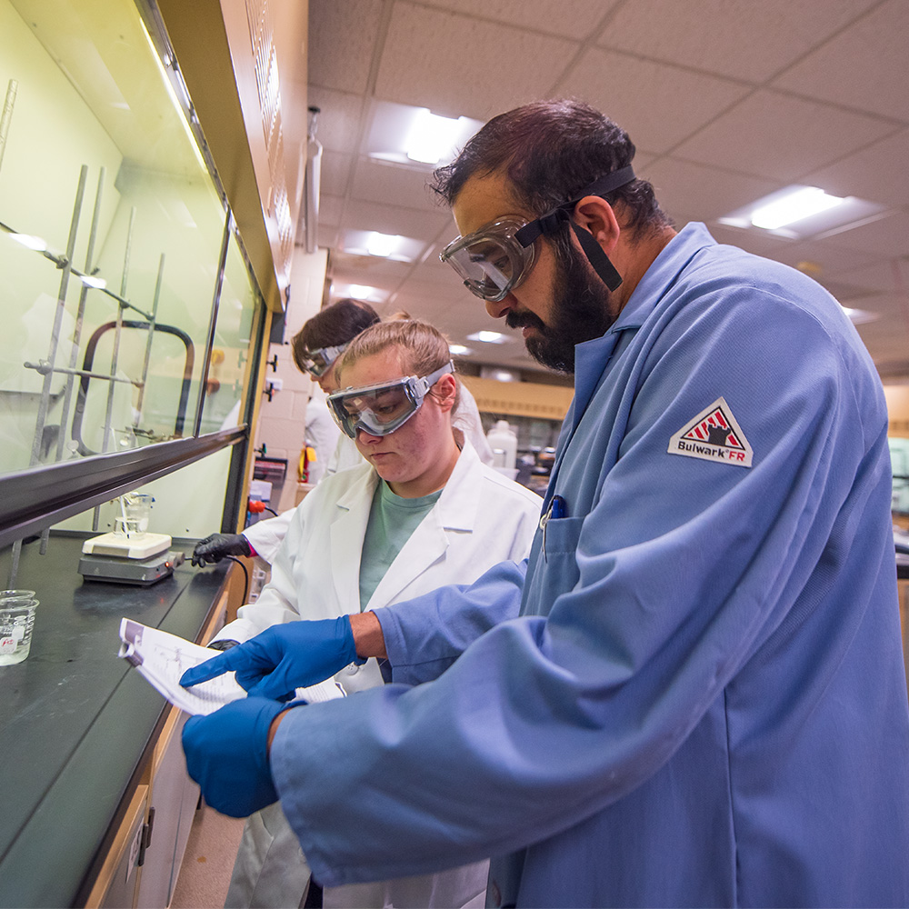 student with professor in a chemistry lab looking over data during an experiment