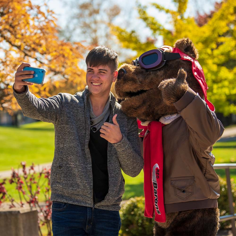 student taking photo with Red Baron mascot